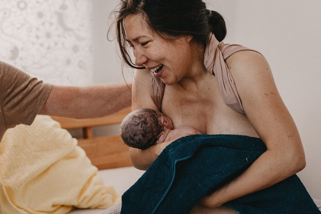 Frau hält zum ersten Mal Baby im Arm Geburtsfotografie Shalynn Crawford Tübingen